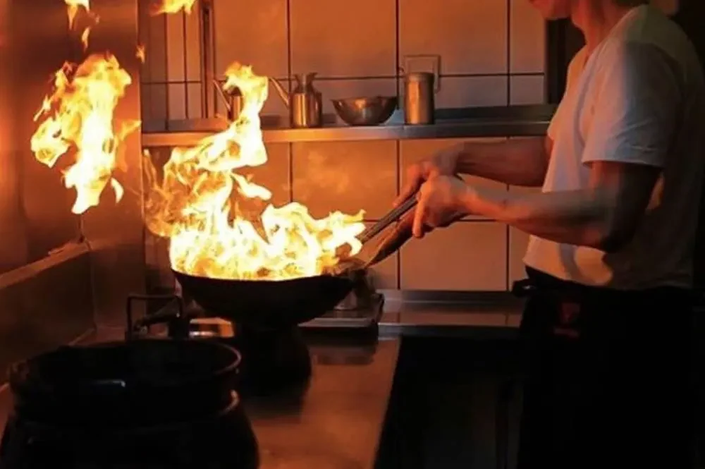 Koch am brennenden Wok in der offenen Küche eines Düsseldorfer Restaurants